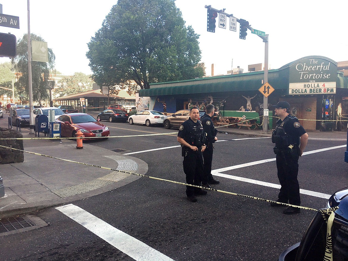 FILE - In this June 29, 2018, file photo, police stand outside across from The Cheerful Tortoise bar at the scene of an earlier shooting in Portland, Ore. Portland State University said Thursday, Aug. 13, 2020, it will disarm its campus police force more than two years after officers from the department shot and killed a Black man who was trying to break up a fight. (Shane Dixon/The Oregonian via AP, File)