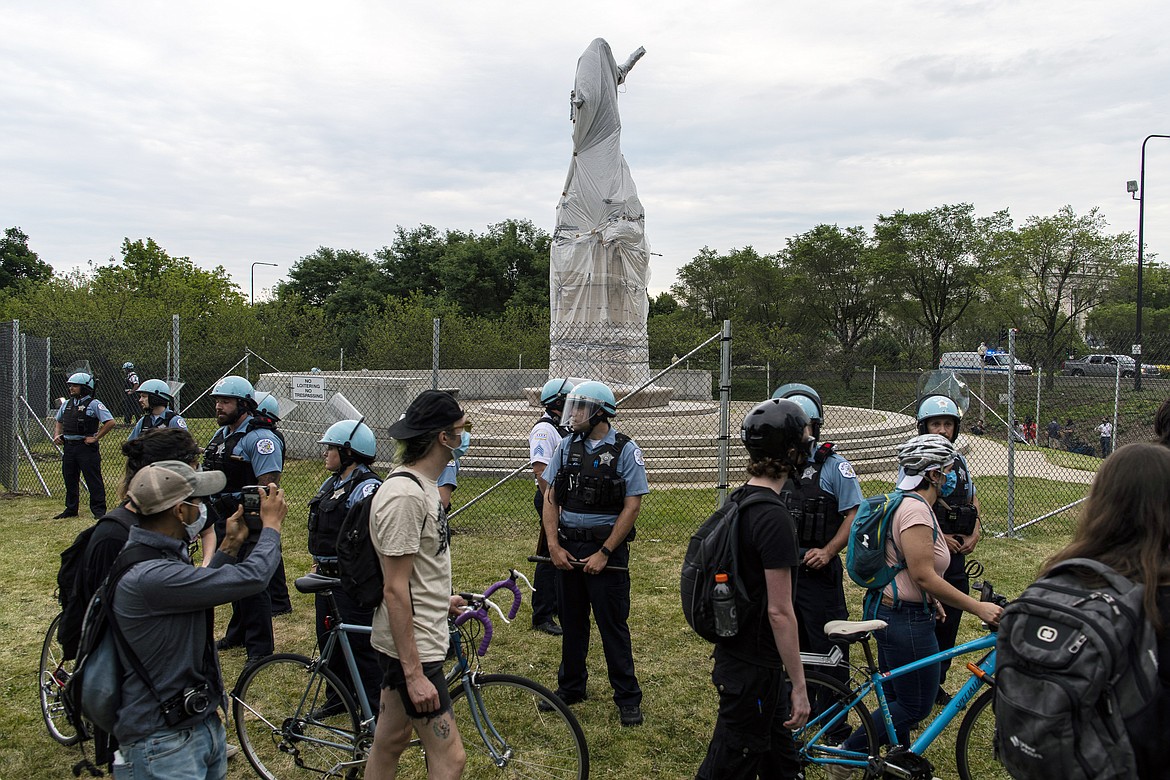 Activists protest around a statue of Christopher Columbus near Roosevelt Rd. and Columbus Dr. while police stand by,, Monday, July 20, 2020 in Chicago. (Tyler LaRiviere/Chicago Sun-Times via AP)