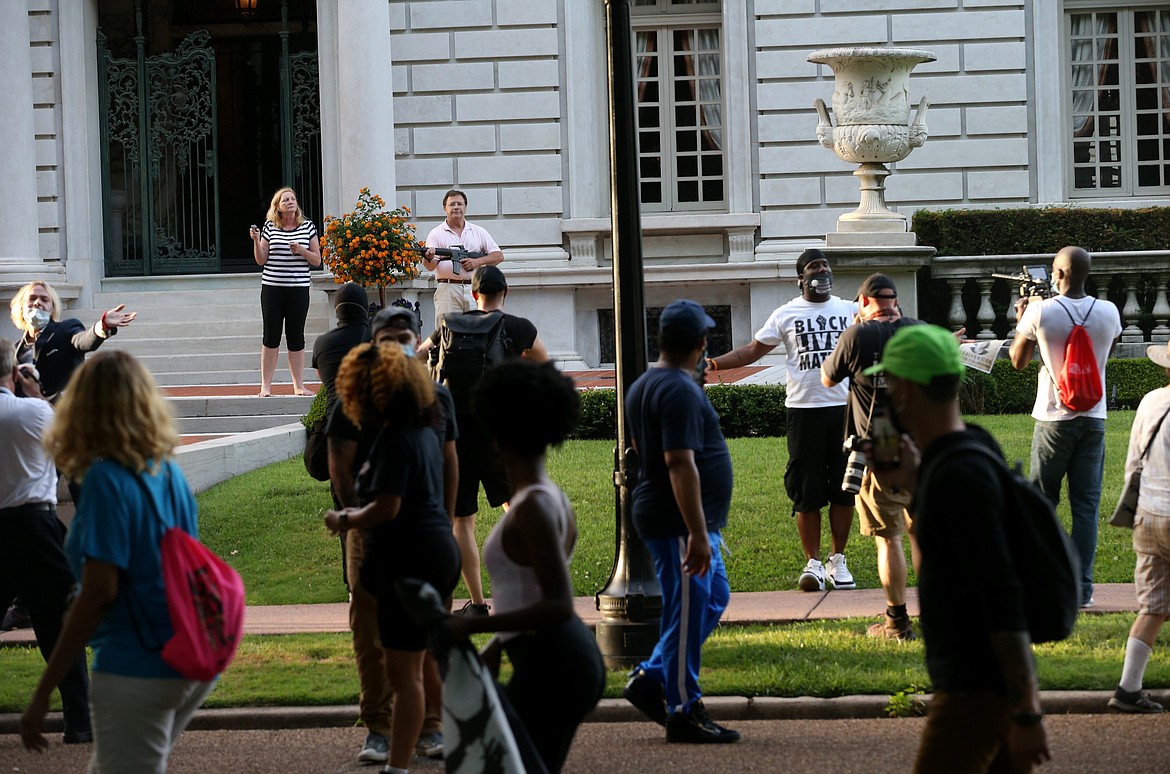 Armed homeowners standing in front their house along Portland Place confront protesters marching to St. Louis Mayor Lyda Krewson's house Sunday, June 28, 2020, in the Central West End of St. Louis. The protesters called for Krewson's resignation for releasing the names and addresses of residents who suggested defunding the police department. (Laurie Skrivan/St. Louis Post-Dispatch via AP)