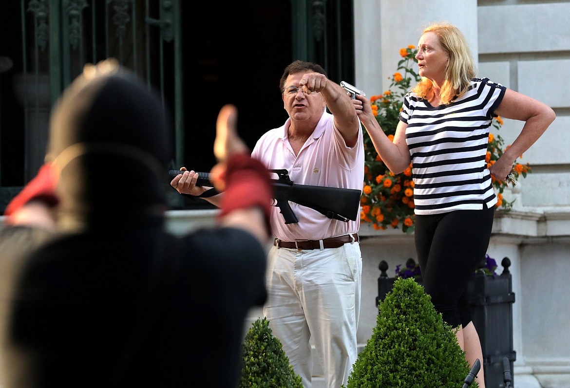 FILE - In this June 28, 2020 file photo, armed homeowners Mark and Patricia McCloskey, standing in front their house along Portland Place confront protesters marching to St. Louis Mayor Lyda Krewson's house in the Central West End of St. Louis. St. Louis’ top prosecutor told The Associated Press on Monday, July 20, 2020 that she is charging a white husband and wife with felony unlawful use of a weapon for displaying guns during a racial injustice protest outside their mansion. (Laurie Skrivan/St. Louis Post-Dispatch via AP File)