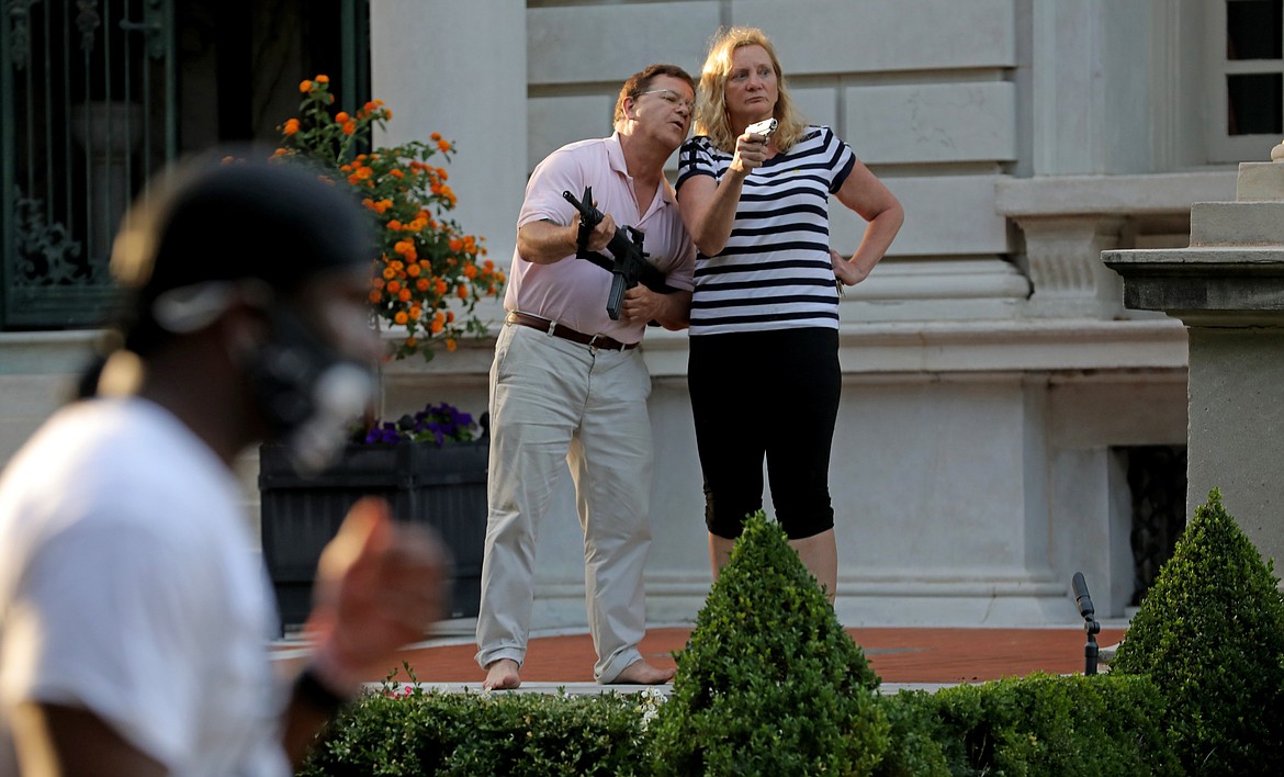 Armed homeowners standing in front their house along Portland Place confront protesters marching to St. Louis Mayor Lyda Krewson's house Sunday, June 28, 2020, in the Central West End of St. Louis. The protesters called for Krewson's resignation for releasing the names and addresses of residents who suggested defunding the police department. (Laurie Skrivan/St. Louis Post-Dispatch via AP)