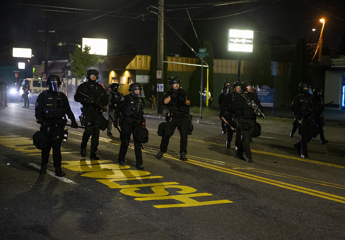 Police gather during a protest in Portland, Ore., on Tuesday, Aug. 4, 2020.  A riot was declared early Wednesday during demonstrations in Portland after authorities said people set fires and barricaded public roadways.(Dave Killen /The Oregonian via AP)