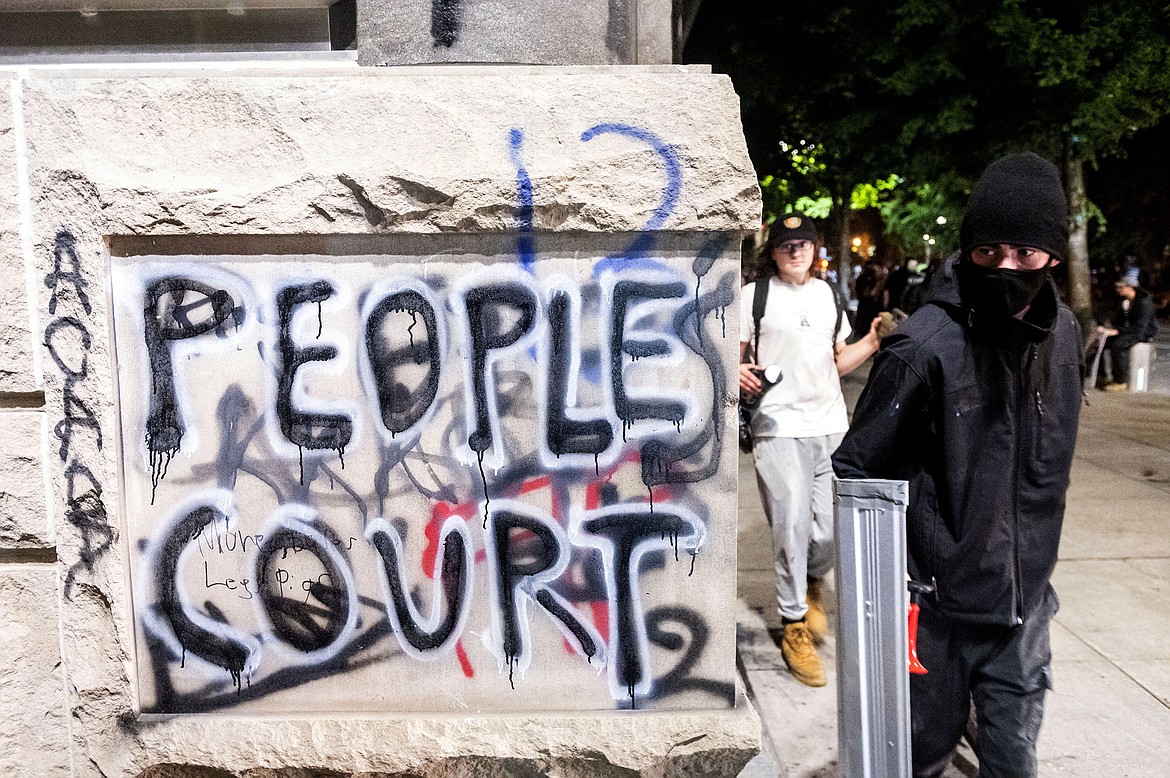 Grafitti is shown during a Black Lives Matter protest outside Mark O. Hatfield United States Courthouse on Monday, July 20, 2020, in Portland, Ore. Portland police early Monday detailed another night of conflict between protesters and federal forces outside the U.S. courthouse in Oregon's largest city, including a small fire outside the building and tear gas deployed to disperse the crowd. (AP Photo/Noah Berger)