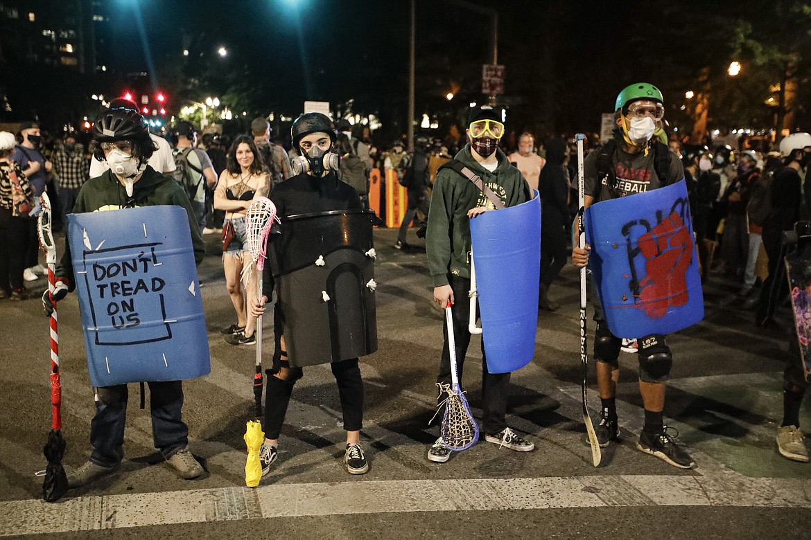 Demonstrators prepare to square off with federal officers during a Black Lives Matter protest at the Mark O. Hatfield United States Courthouse Tuesday, July 28, 2020, in Portland, Ore. (AP Photo/Marcio Jose Sanchez)