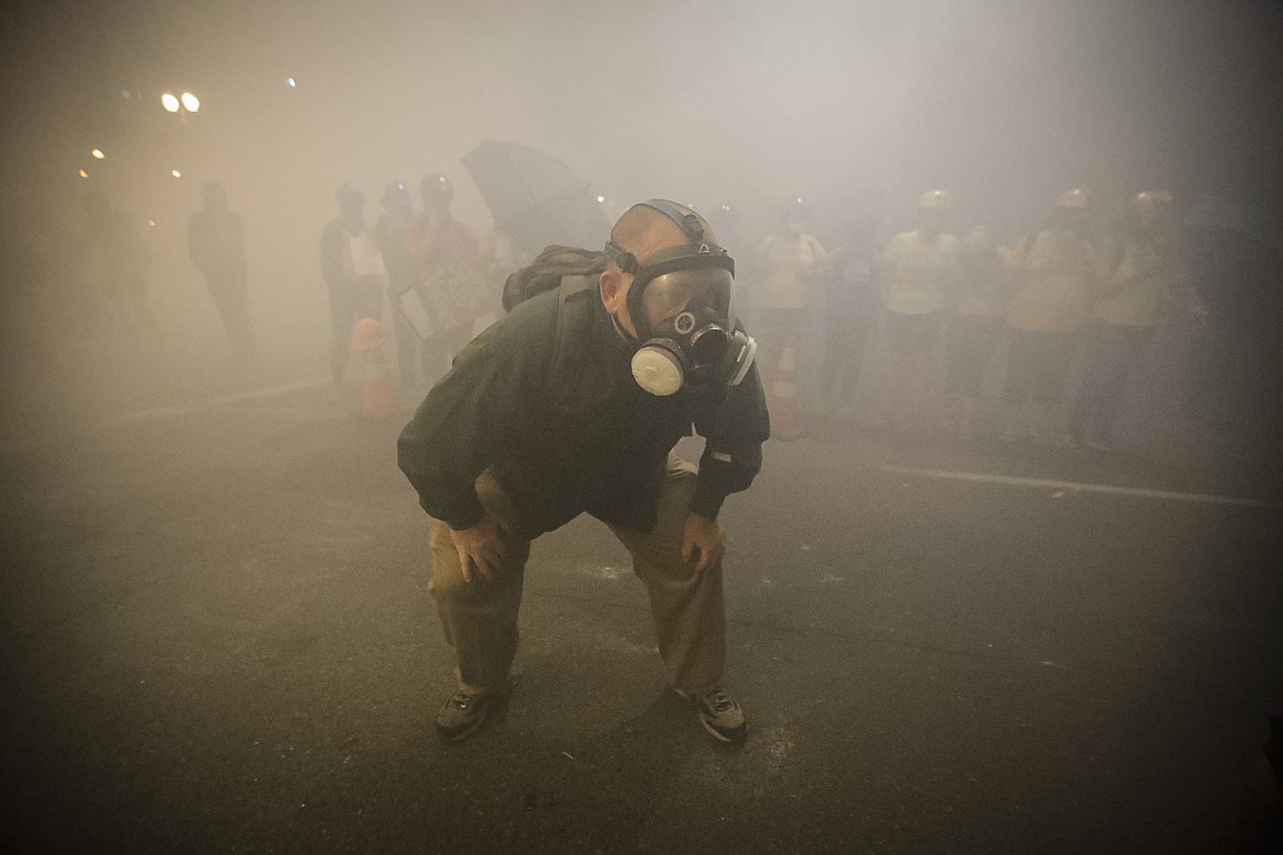 A demonstrator wears a gas mask as federal officers deploy tear gas during a Black Lives Matter protest at the Mark O. Hatfield United States Courthouse Monday, July 27, 2020, in Portland, Ore. (AP Photo/Marcio Jose Sanchez)