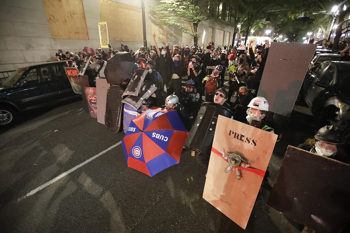 EDS NOTE: OBSCENITY - Demonstrators shield themselves from advancing federal officers during a Black Lives Matter protest Tuesday, July 28, 2020, in Portland, Ore. (AP Photo/Marcio Jose Sanchez)