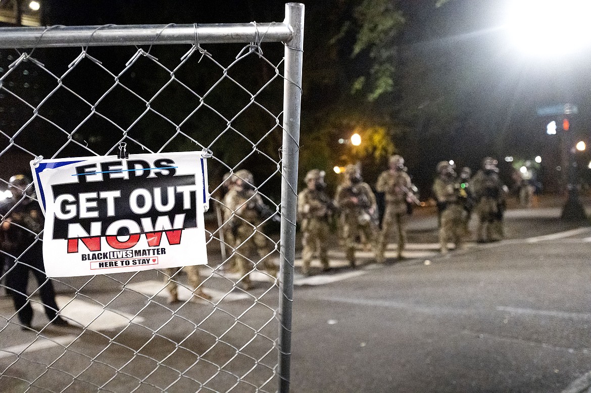 Federal agents disperse Black Lives Matter protesters near the Mark O. Hatfield United States Courthouse on Monday, July 20, 2020, in Portland, Ore. Officers used teargas and projectiles to move the crowd after some protesters tore down a fence fronting the courthouse. (AP Photo/Noah Berger)