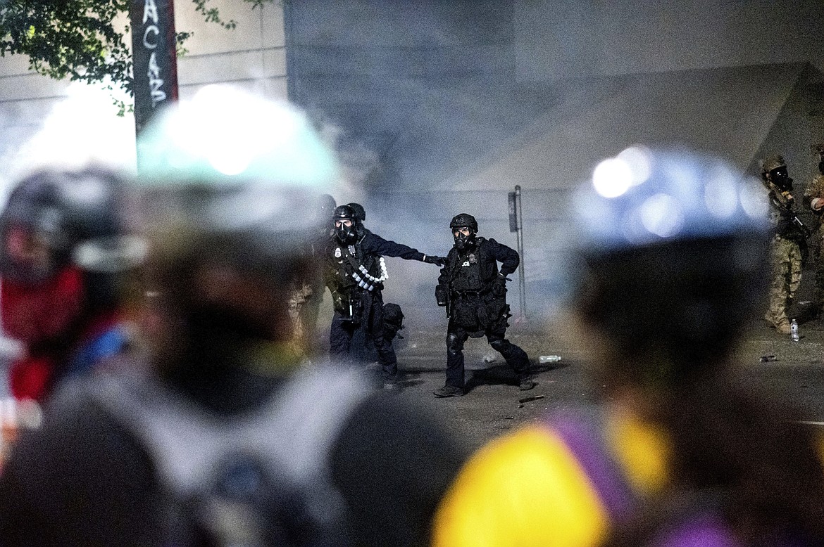 Federal officers prepare to disperse Black Lives Matter protesters at the Mark O. Hatfield United States Courthouse on Tuesday, July 21, 2020, in Portland, Ore.  A federal judge is hearing arguments on Oregon's request for a restraining order against federal agents who have been sent to the state's largest city to quell protests that have spiraled into nightly clashes between authorities and demonstrators. (AP Photo/Noah Berger)