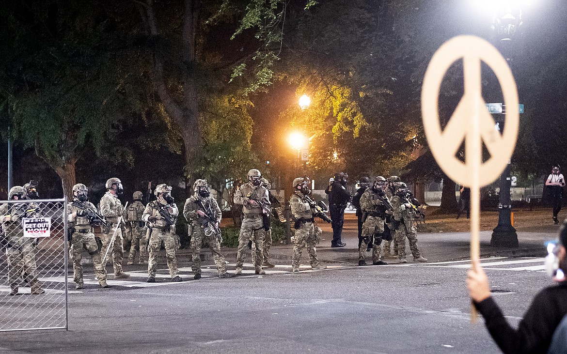 Federal agents disperse Black Lives Matter protesters near the Mark O. Hatfield United States Courthouse on Monday, July 20, 2020, in Portland, Ore. Officers used teargas and projectiles to move the crowd after some protesters tore down a fence fronting the courthouse. (AP Photo/Noah Berger)