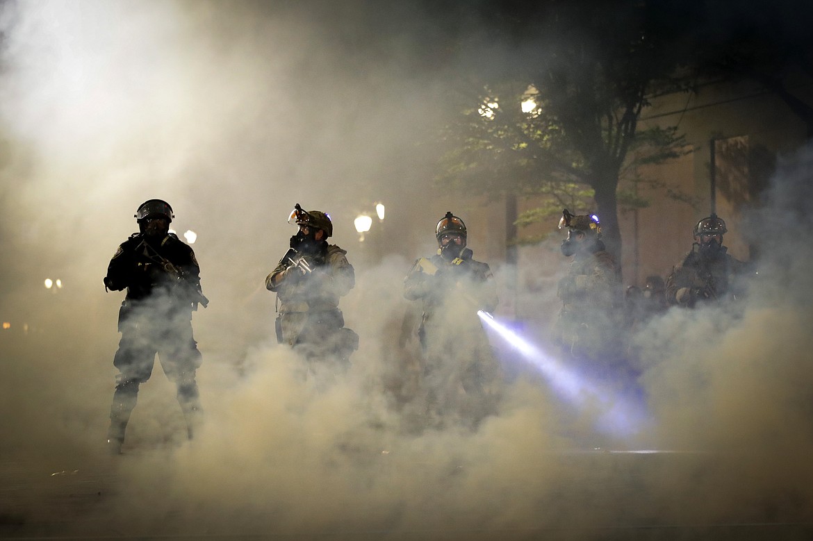 Federal officers are surrounded by smoke as they push back demonstrators during a Black Lives Matter protest at the Mark O. Hatfield United States Courthouse Wednesday, July 29, 2020, in Portland, Ore. (AP Photo/Marcio Jose Sanchez)