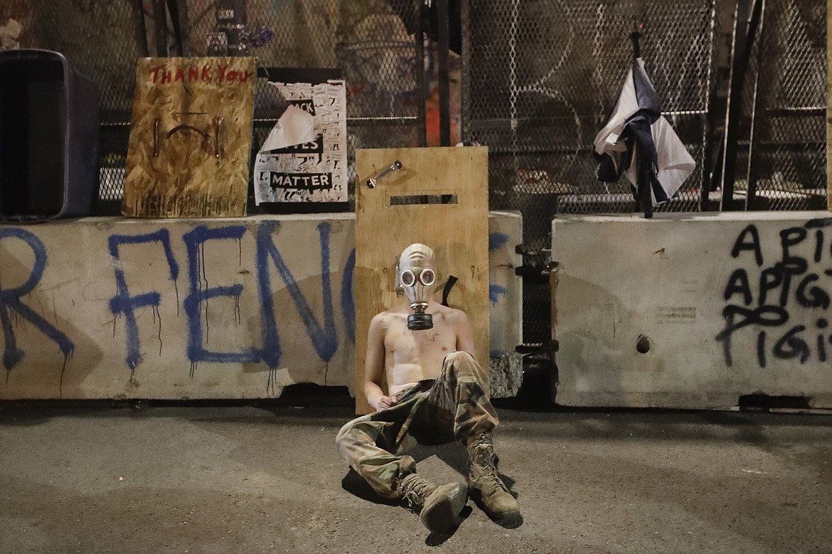 A demonstrator rests after federal officers retreat back into the Mark O. Hatfield United States Courthouse during a Black Lives Matter protest Wednesday, July 29, 2020, in Portland, Ore. (AP Photo/Marcio Jose Sanchez)