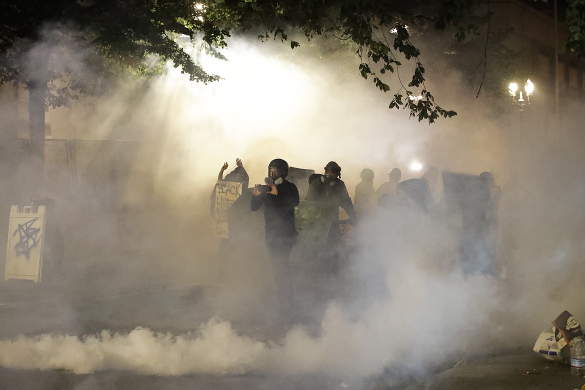 A group of demonstrators huddle as they are tear-gassed by federal officers during a Black Lives Matter protest at the Mark O. Hatfield United States Courthouse Tuesday, July 28, 2020, in Portland, Ore. (AP Photo/Marcio Jose Sanchez)