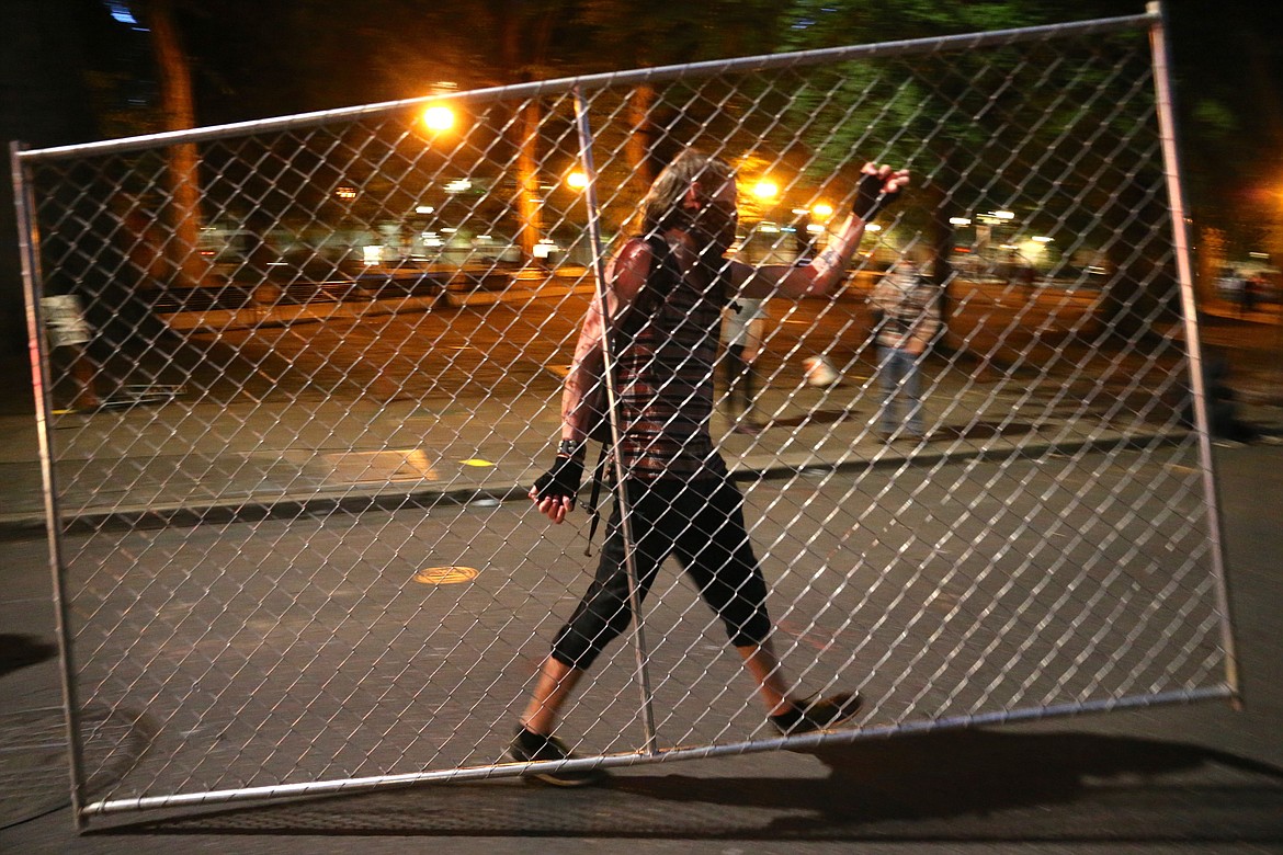 Protesters relocate a fence in front of the Justice Center, Saturday, July 18, 2020, during another night of protests in Portland, Ore. (Mark Graves/The Oregonian via AP)