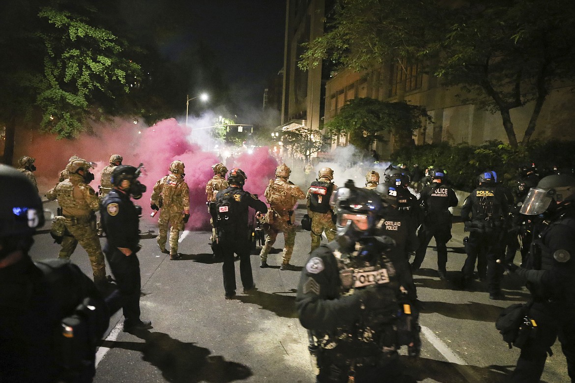 Police respond to protesters during a demonstration,  Friday, July 17, 2020 in Portland, Ore. Militarized federal agents deployed by the president to Portland, fired tear gas against protesters again overnight as the city’s mayor demanded that the agents be removed and as the state’s attorney general vowed to seek a restraining order against them. (Dave Killen/The Oregonian via AP)