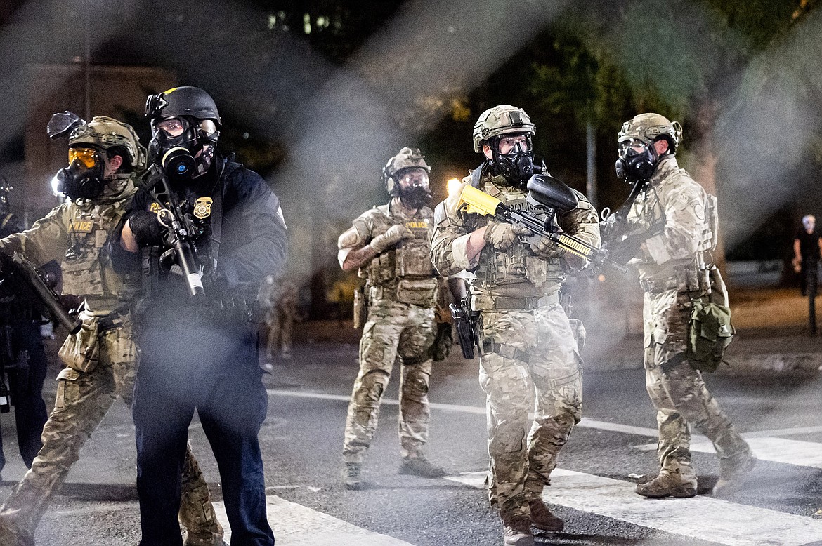 Federal agents disperse Black Lives Matter protesters near the Mark O. Hatfield United States Courthouse on Monday, July 20, 2020, in Portland, Ore. Officers used teargas and projectiles to move the crowd after some protesters tore down a fence fronting the courthouse. (AP Photo/Noah Berger)