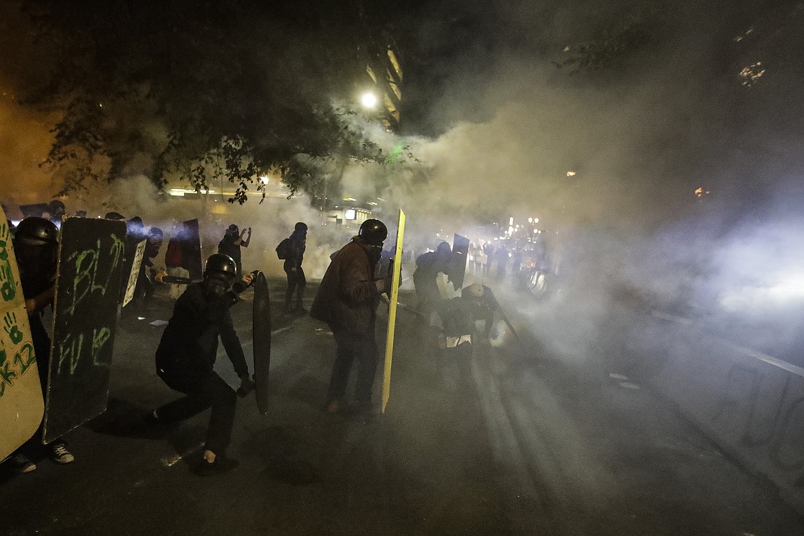 Demonstrators shield themselves from crowd control munitions and tear gas launched by federal officers during a Black Lives Matter protest at the Mark O. Hatfield United States Courthouse Wednesday, July 29, 2020, in Portland, Ore. (AP Photo/Marcio Jose Sanchez)