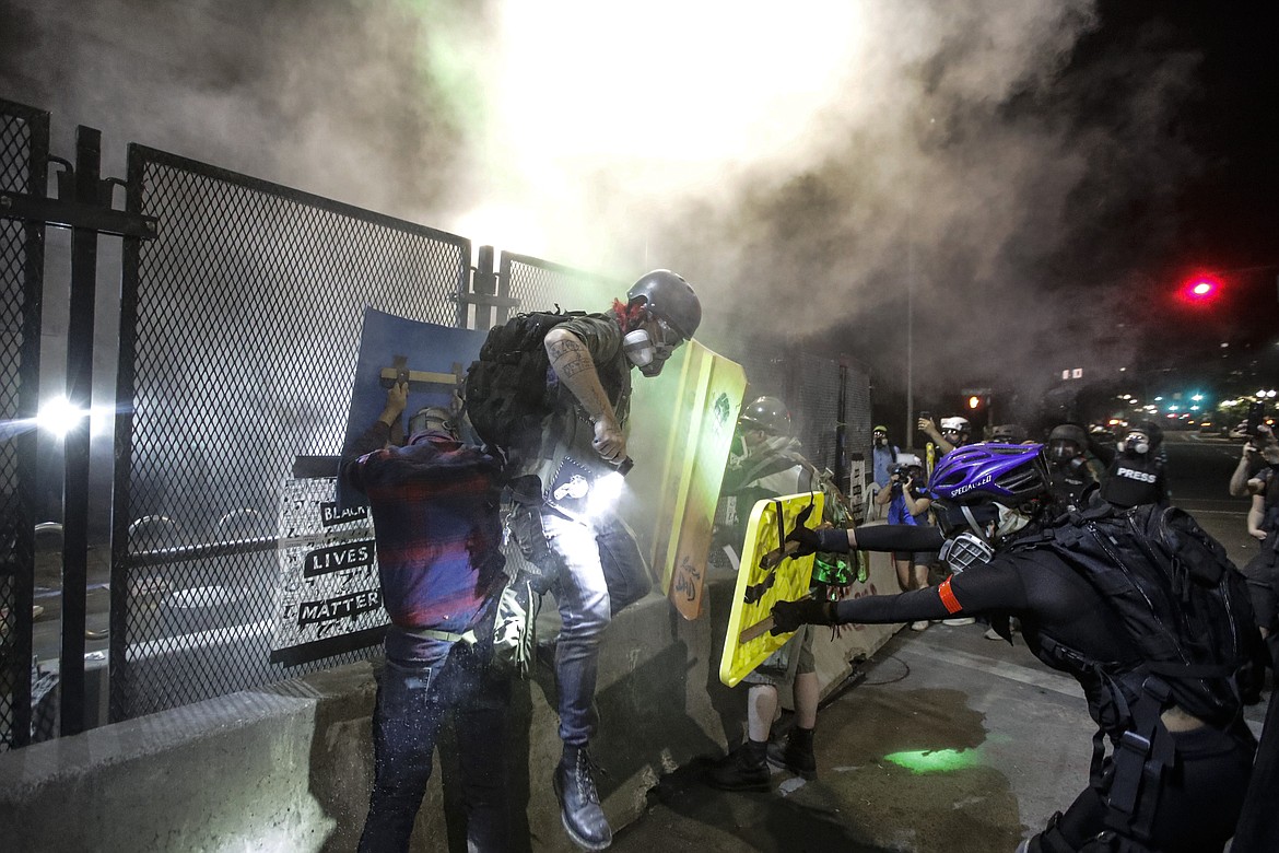 Demonstrators retreat as federal officer launch tear gas on them during a Black Lives Matter protest at the Mark O. Hatfield United States Courthouse Wednesday, July 29, 2020, in Portland, Ore. (AP Photo/Marcio Jose Sanchez)