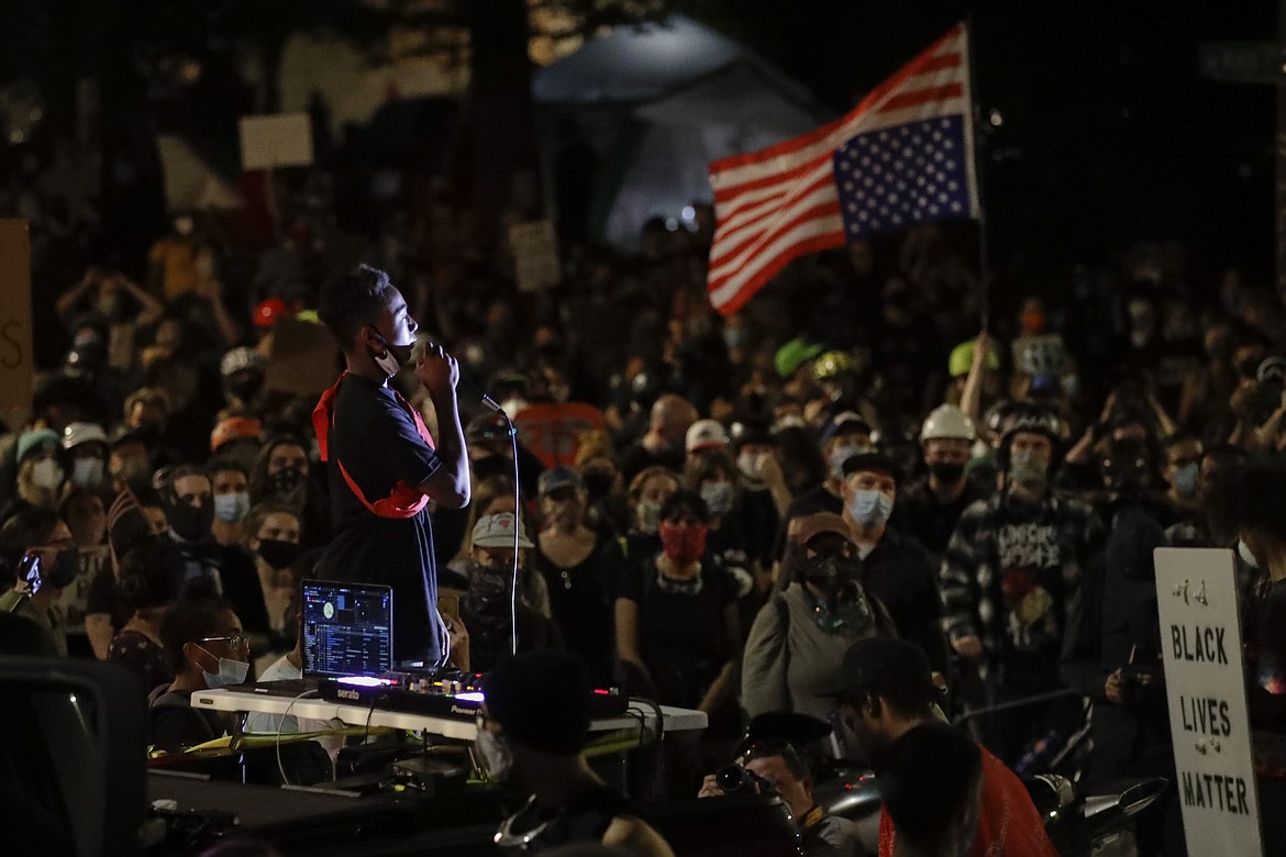 A demonstrator speaks to a crowd from the bed of a pickup truck during a Black Lives Matter protest at the Mark O. Hatfield United States Courthouse Sunday, July 26, 2020, in Portland, Ore. (AP Photo/Marcio Jose Sanchez)