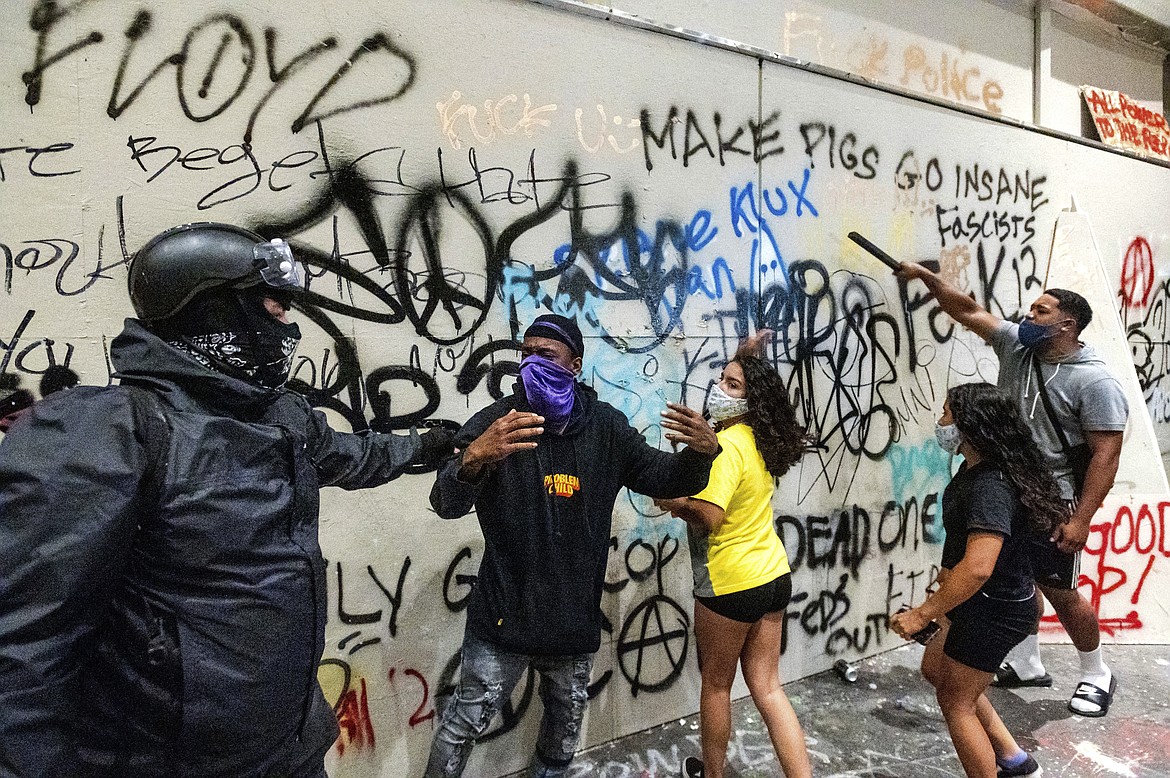 Black Lives Matter protesters gather at the Mark O. Hatfield United States Courthouse on Tuesday, July 21, 2020, in Portland, Ore. Demonstrators removed portions of the boarding, which cover the building's ground floor, before federal officers used chemical irritants and rubber bullets to disperse them. (AP Photo/Noah Berger)