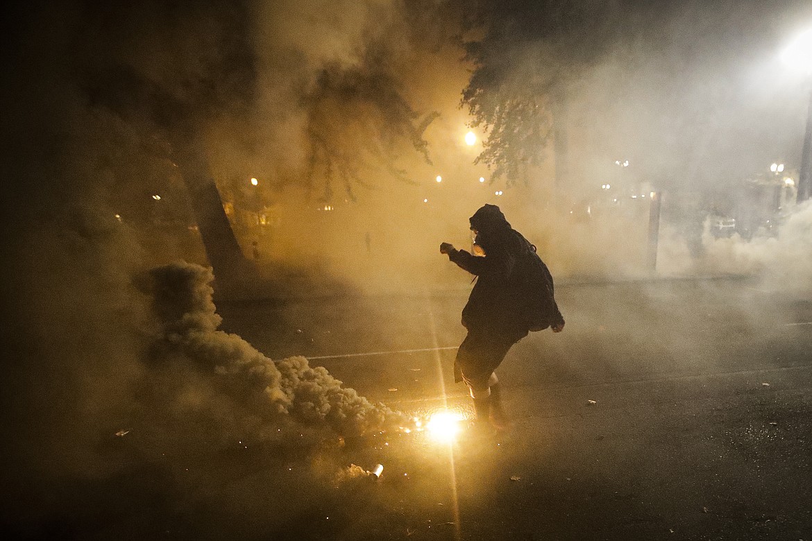 A demonstrator kicks back a tear gas canister back at federal officers during a Black Lives Matter protest at the Mark O. Hatfield United States Courthouse Wednesday, July 29, 2020, in Portland, Ore. (AP Photo/Marcio Jose Sanchez)