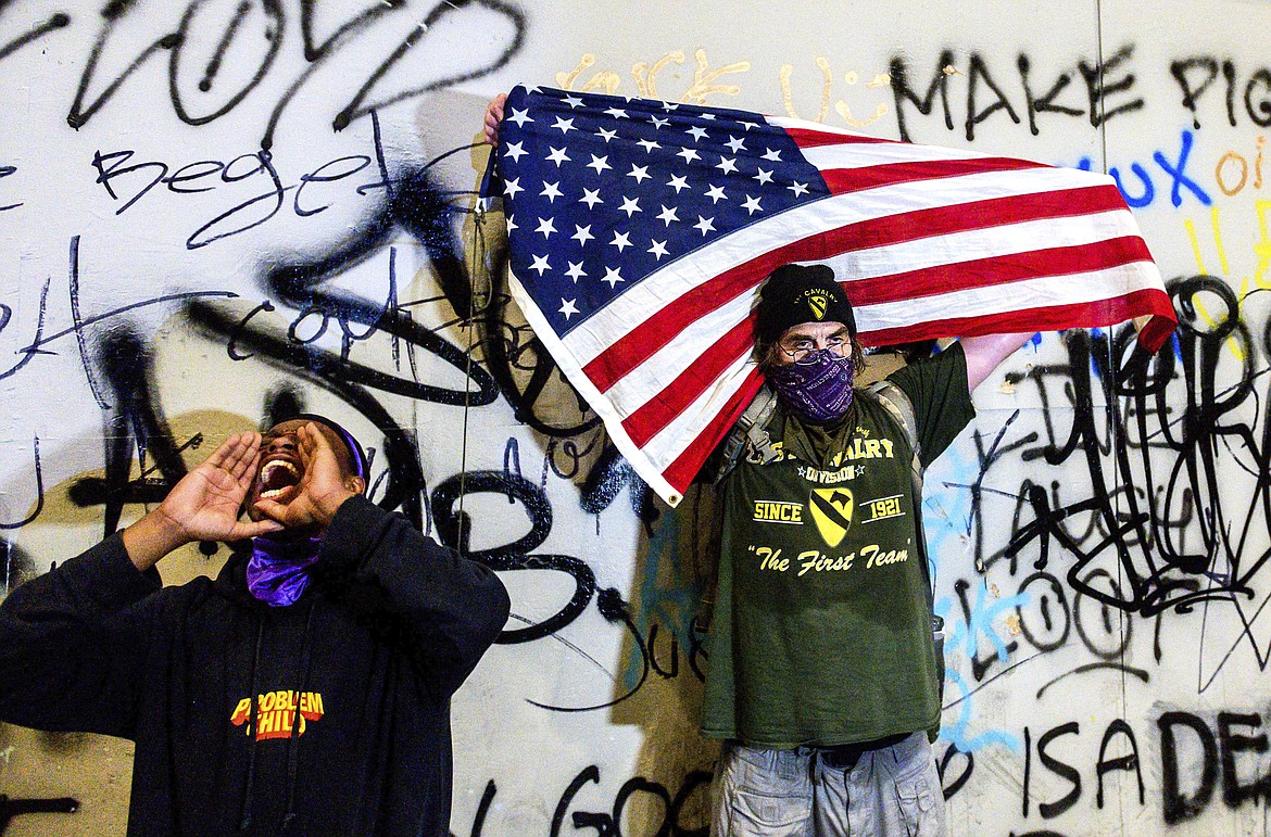 Black Lives Matter protesters gather at the Mark O. Hatfield United States Courthouse on Tuesday, July 21, 2020, in Portland, Ore. Demonstrators removed portions of the boarding, which cover the building's ground floor, before federal officers used chemical irritants and rubber bullets to disperse them. (AP Photo/Noah Berger)