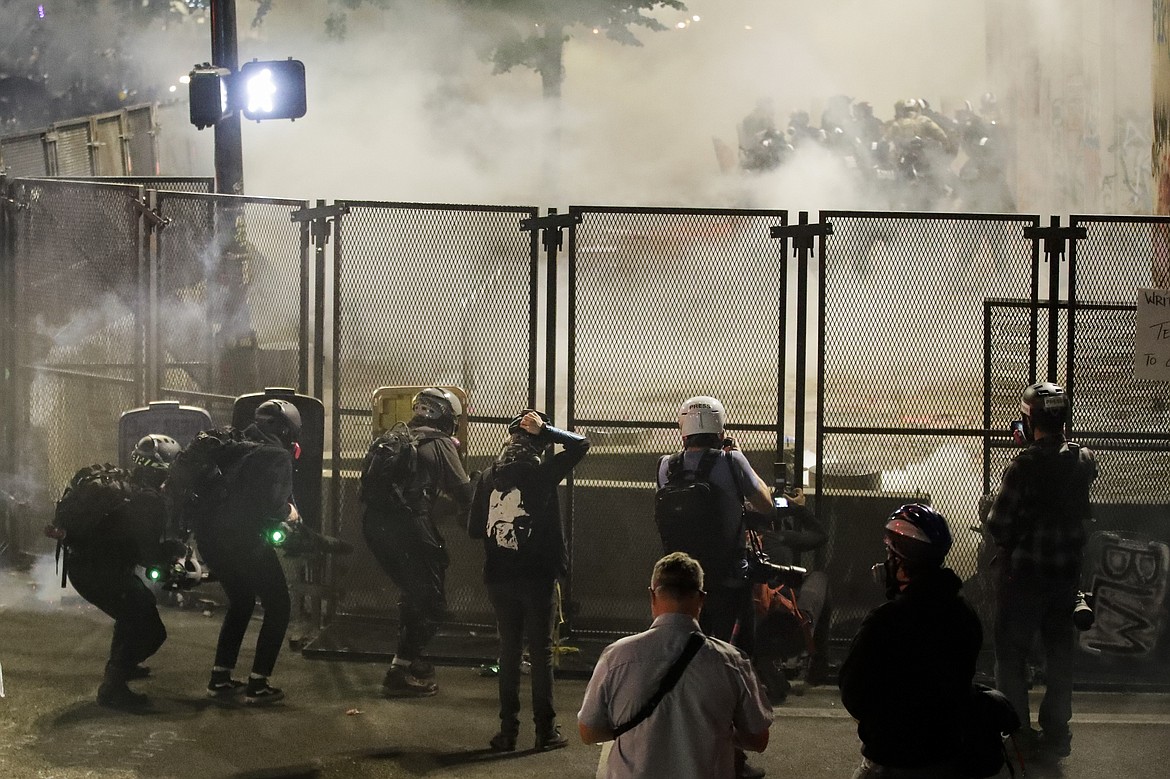 Demonstrators use make shift shields to protect themselves from federal officers, top, right, during a Black Lives Matter protest at the Mark O. Hatfield United States Courthouse Sunday, July 26, 2020, in Portland, Ore. (AP Photo/Marcio Jose Sanchez)