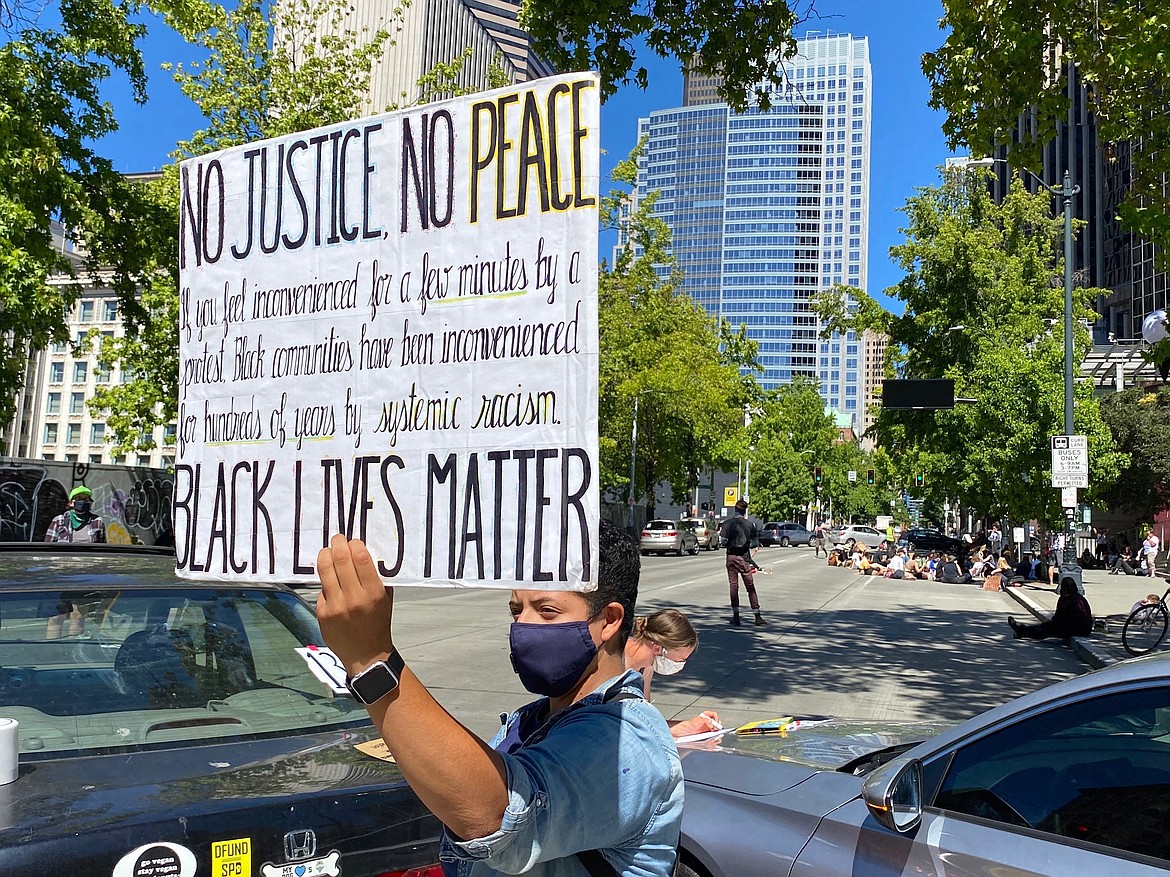 Protestors gather outside city hall for Monday's Seattle City Council budget committee voting, which includes potential Seattle Police Department cuts, on Monday,  Aug. 10, 2020. (Erika Schultz/The Seattle Times via AP)