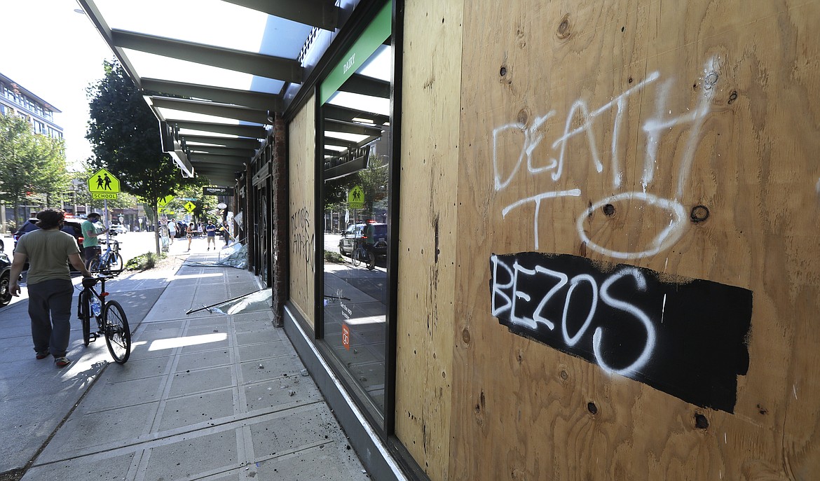 Graffiti reads "Death to Bezos" on the boarded up window of the Amazon Go grocery store in reference to Amazon founder and CEO Jeff Bezos, Sunday, July 19, 2020 in Seattle. Protesters broke windows at the store earlier in the afternoon. (AP Photo/Ted S. Warren)