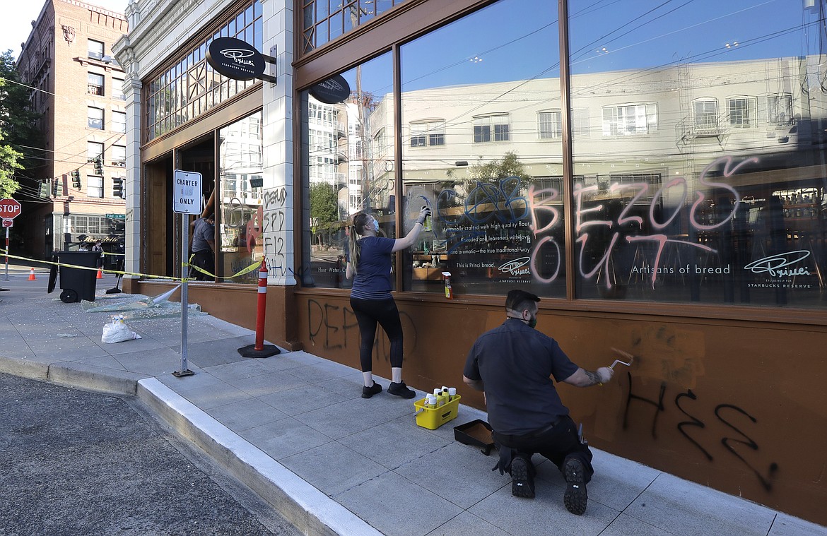 Workers clean up graffiti at the Starbucks Roastery, Sunday, July 19, 2020 in Seattle's Capitol Hill neighborhood. Protesters broke windows at the store earlier in the afternoon. (AP Photo/Ted S. Warren)