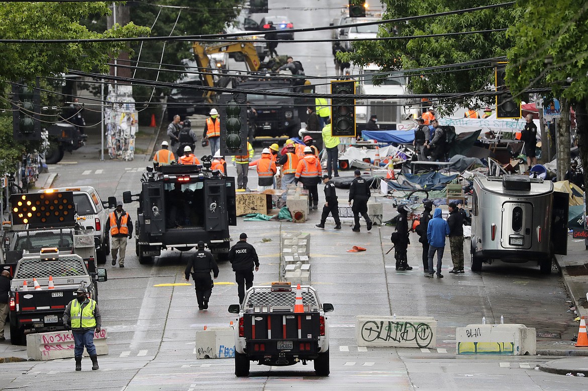 Police and city workers fill a street occupied hours earlier by an encampment of protesters Wednesday, July 1, 2020, in Seattle, where streets had been blocked off in an area demonstrators had occupied for weeks. Seattle police showed up in force earlier in the day at the "occupied" protest zone, tore down demonstrators' tents and used bicycles to herd the protesters after the mayor ordered the area cleared following two fatal shootings in less than two weeks. The "Capitol Hill Occupied Protest" zone was set up near downtown following the death of George Floyd while in police custody in Minneapolis. (AP Photo/Elaine Thompson)
