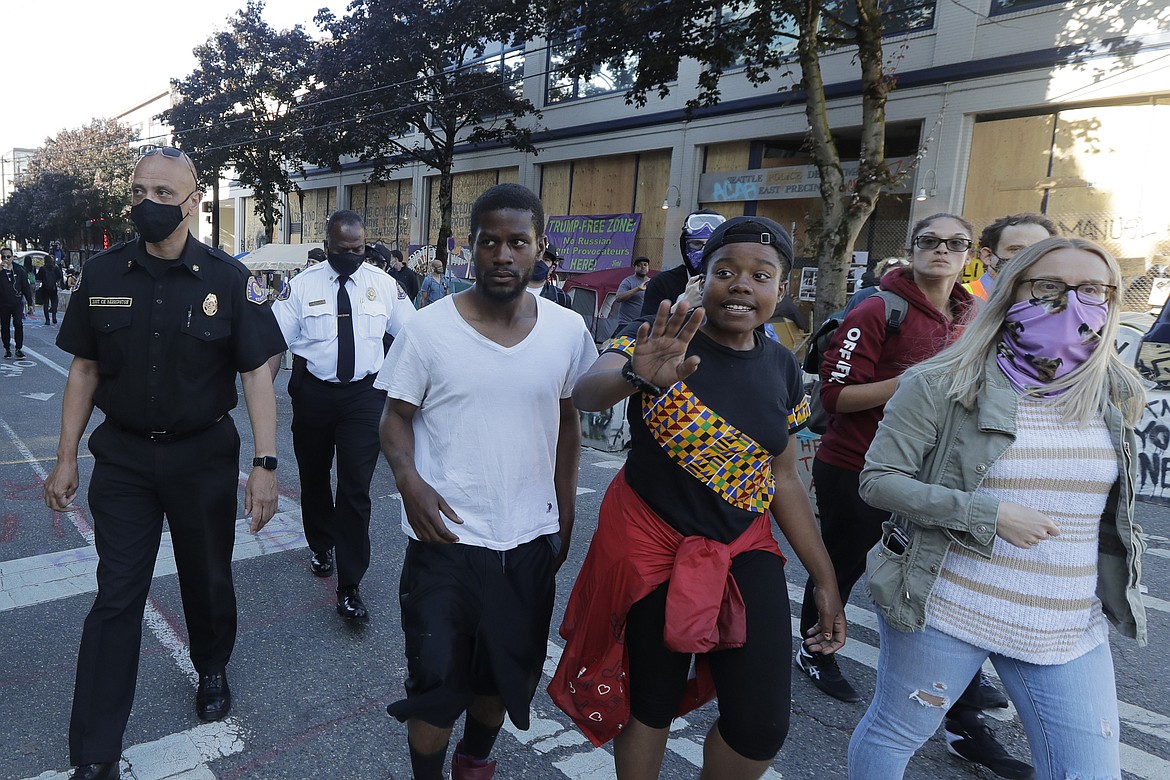 Seattle Fire Assistant Chief Willie Barrington, left, and Chief Harold Scoggins, second from left, walk with protest organizers, Friday, June 26, 2020 inside the CHOP (Capitol Hill Occupied Protest) zone in Seattle. The officials were on hand to try and negotiate with protesters after workers and trucks from the Seattle Department of Transportation who had arrived with the intention of removing barricades were met with resistance. The area has been occupied by protesters since Seattle Police pulled back from their East Precinct building following violent clashes with demonstrators earlier in the month. (AP Photo/Ted S. Warren)