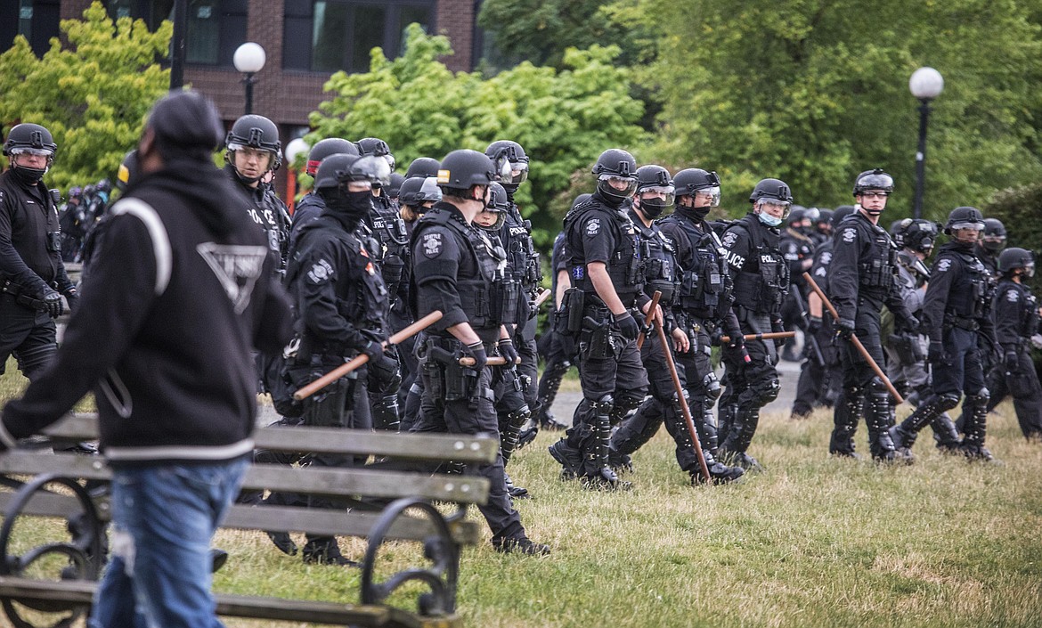 Seattle Police walk across Cal Anderson Park Wednesday, July 1, 2020, in Seattle as they sweep people away.  (Steve Ringman/The Seattle Times via AP)