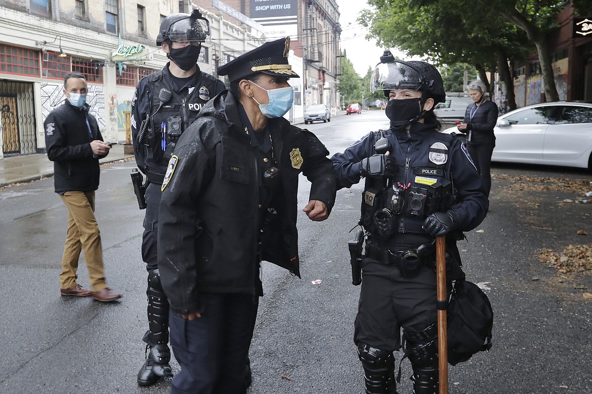 Seattle Police Chief Carmen Best, center, bumps elbows in greeting with an officer as the chief walks the perimeter of an area police cleared hours earlier Wednesday, July 1, 2020, in Seattle, where streets had been blocked off in an area demonstrators had occupied for weeks. Seattle police showed up in force earlier in the day at the "occupied" protest zone, tore down demonstrators' tents and used bicycles to herd the protesters after the mayor ordered the area cleared following two fatal shootings in less than two weeks. The "Capitol Hill Occupied Protest" zone was set up near downtown following the death of George Floyd while in police custody in Minneapolis. (AP Photo/Elaine Thompson)