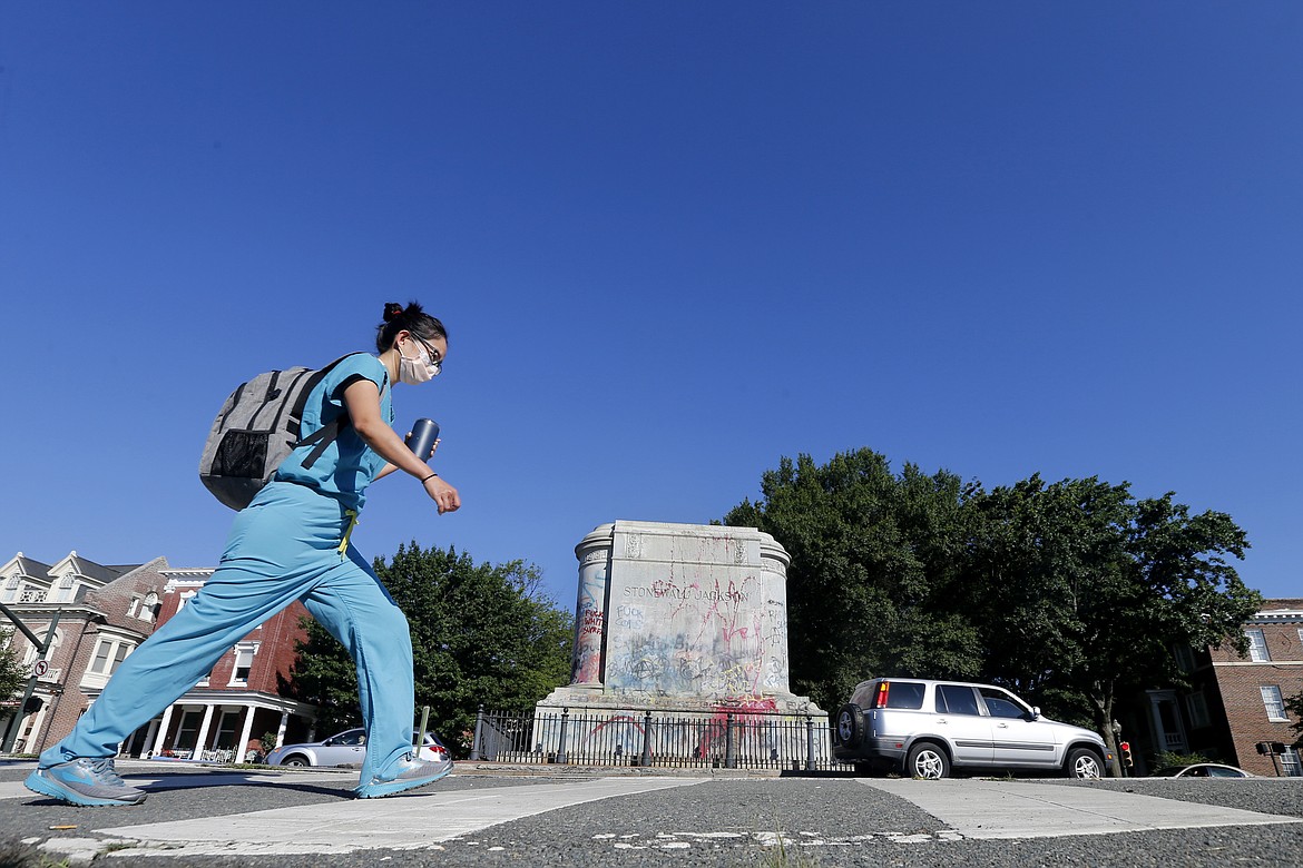 EDS NOTE: OBSCENITY - A passerby walks past the pedestal where the statue of Confederate General Stonewall Jackson was removed on Monument Avenue, Thursday July 2, 2020, in Richmond, Va. (AP Photo/Steve Helber)