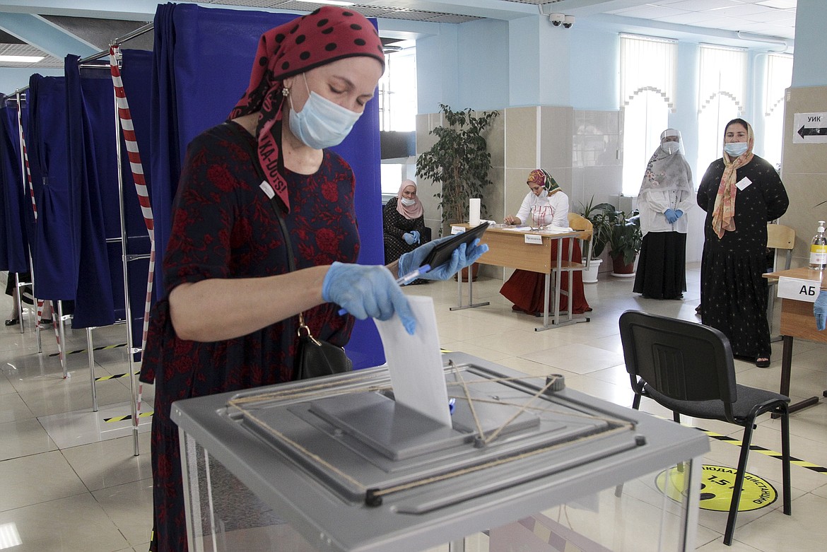 A woman, wearing a face mask to protect against coronavirus casts her ballot, observes social distancing guidelines, at a polling station in Grozny, Russia, Wednesday, July 1, 2020. Russia's vote on constitutional amendments that could allow President Vladimir Putin to extend his rule until 2036 entered its final day Wednesday amid widespread reports of pressure on voters and other irregularities. (AP Photo/Musa Sadulayev)