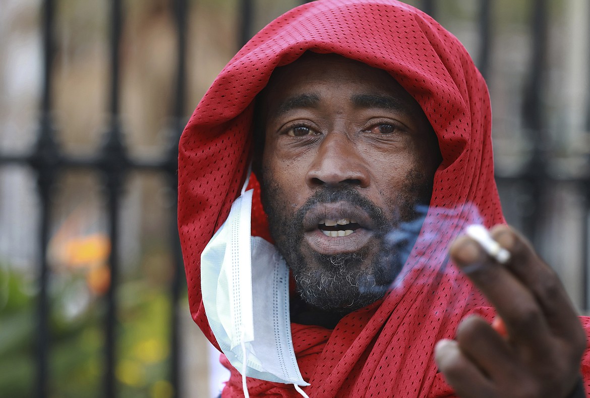 FILE — In this June 2, 2020 file photo, a demonstrator exhales smoke during a protest against the tobacco ban outside parliament in Cape Town, South Africa. South Africa is three months into a ban on the sale of cigarettes and other tobacco products, an unusual tactic employed by a government to protect the health of its citizens during the coronavirus pandemic. The country is one of just a few around the world to have banned tobacco sales during the pandemic and the only one to still have it in place.  (AP Photo/Nardus Engelbrecht/File)