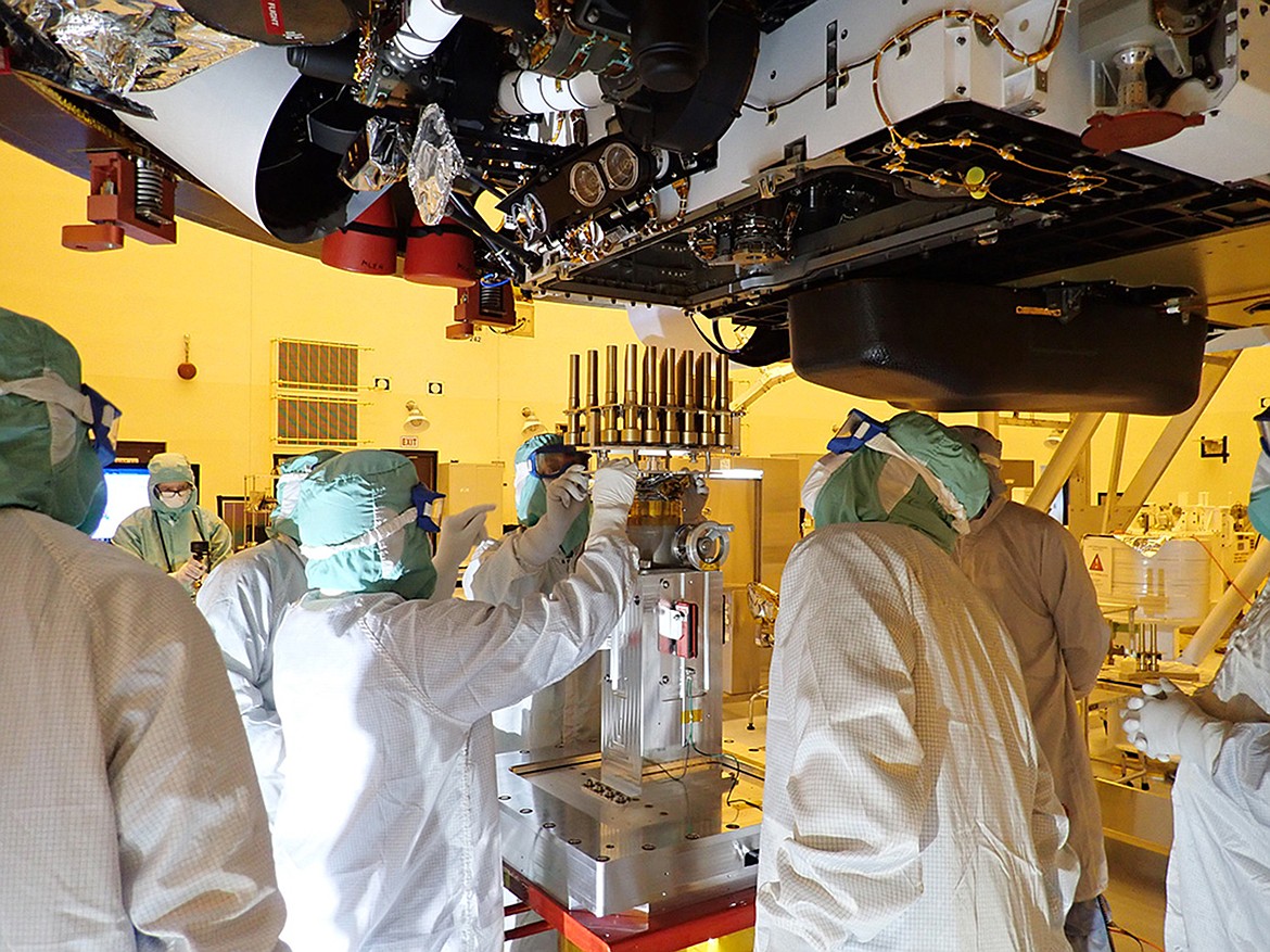 In this May 20, 2020 photo made available by NASA/JPL-Caltech, engineers and technicians insert sample tubes into the belly of the Perseverance Mars rover at the Kennedy Space Center in Florida. NASA is upping the ante with its newest rover headed to Mars. Set to rocket away this week from Florida, Perseverance is NASA's brawniest and brainiest Martian rover yet.  (NASA/JPL-Caltech via AP)