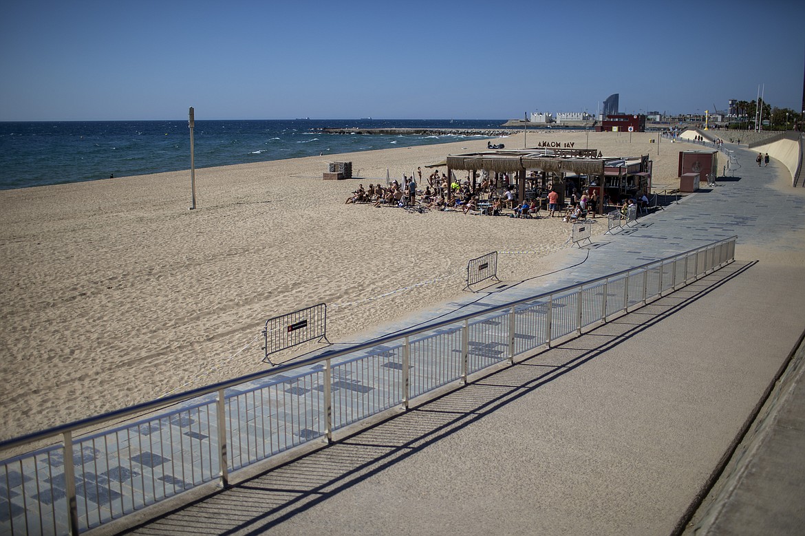 People sit on a terrace in a beach where access is no allowed in that time slot, in Barcelona, Spain, on Wednesday, May 27, 2020. Roughly half of the population, including residents in the biggest cities of Madrid and Barcelona, are entering phase 1, which allows social gatherings in limited numbers, restaurant and bar service with outdoor sitting and some cultural and sports activities. (AP Photo/Emilio Morenatti)