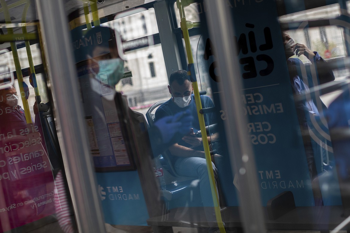 Commuters wear face masks inside a bus in Madrid, Spain on Sunday, March 22, 2020. Spanish health authorities have acknowledged that some intensive care units in the hardest-hit areas are close to their limit. The army was building a field hospital with 5,500 beds in a convention center in Madrid, where hotels are also being turned into wards for virus patients without serious breathing problems. For most people, the new coronavirus causes only mild or moderate symptoms. For some it can cause more severe illness. (AP Photo/Bernat Armangue)