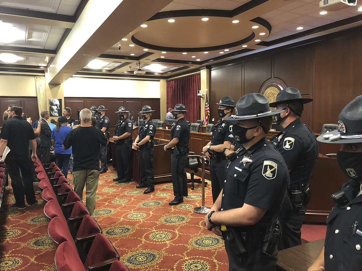 Idaho State Police form a row in a committee meeting room in the Idaho Statehouse in Boise, Idaho, on Tuesday, Aug. 25, 2020. One person was taken into custody and lawmakers abandoned the room after spectators at a House committee meeting at the Idaho Statehouse became disruptive. The committee left the room as at least a dozen Idaho State Police formed a shield between them and the crowd of more than 100.