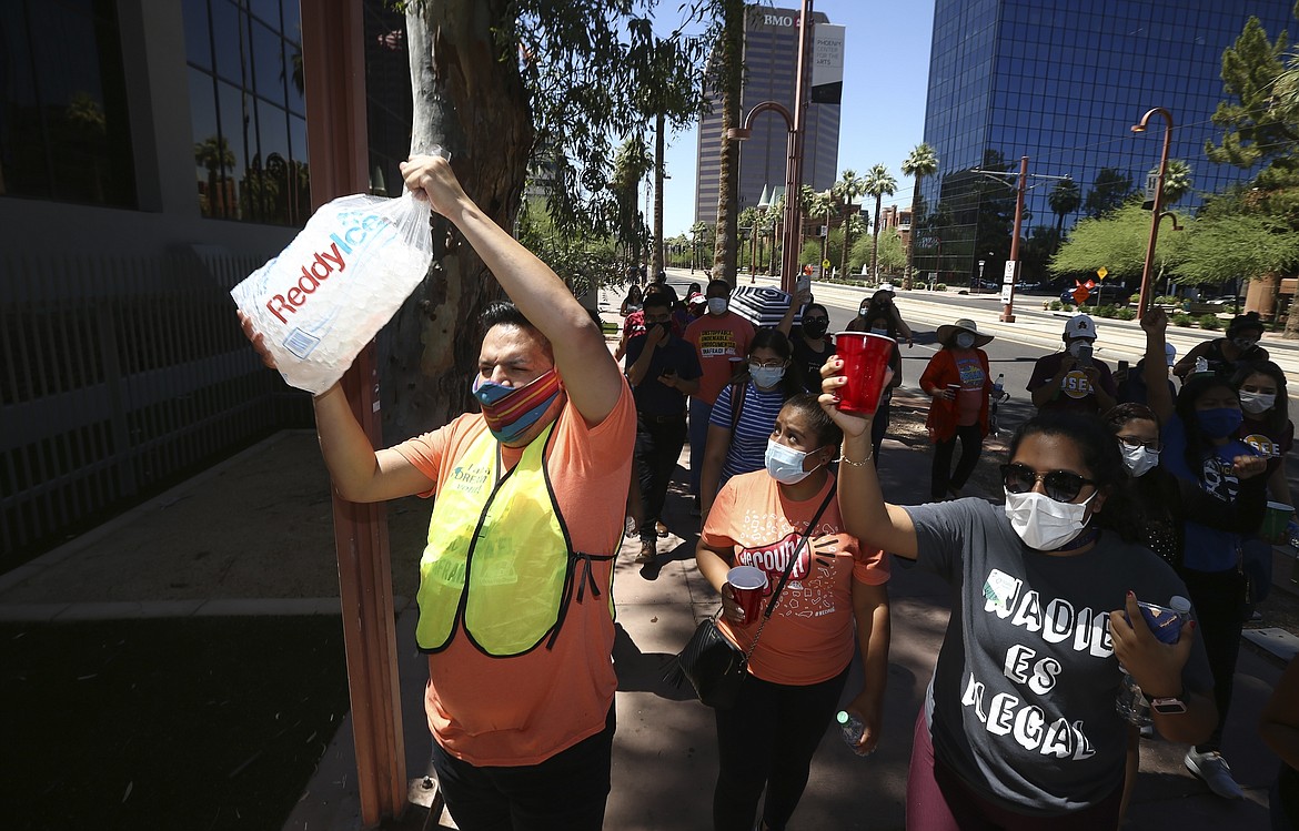 Protesters, many of them Deferred Action for Childhood Arrivals recipients, carry ice in front of the U.S. Immigration and Customs Enforcement building after the U.S. Supreme Court ruled on the DACA program Thursday, June 18, 2020, in Phoenix. The U.S. Supreme Court ruled President Donald Trump improperly ended the program that protects immigrants brought to the country as children and allows them to legally work, keeping the people enrolled in DACA. (AP Photo/Ross D. Franklin)