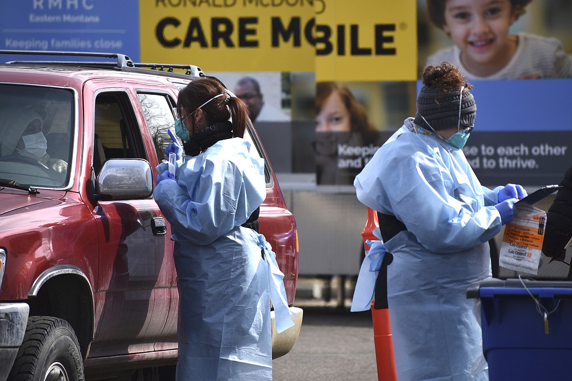 Critical care nurse Molly Spaeny, left, with St. Vincent Healthcare speaks with a patient after administering a coronavirus test in a drive-thru testing center outside the hospital in Billings, Mont. on March 20, 2020. For most people, the new coronavirus causes only mild or moderate symptoms, such as fever and cough. For some, especially older adults and people with existing health problems, it can cause more severe illness, including pneumonia.(AP Photo/Matthew Brown)