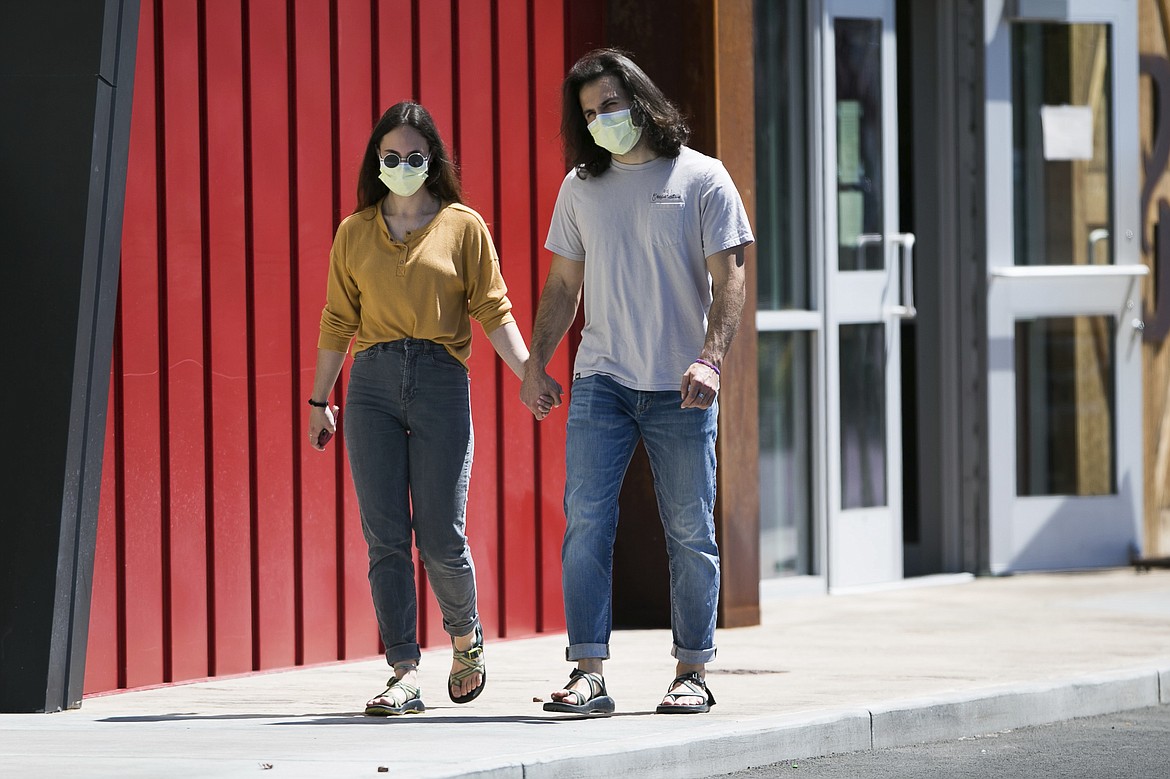 Hana Morris, left, and Forrest Golic wear masks as they walk hand in hand Monday, June 22, 2020, in Yakima, Wash. Washington state will require people to wear facial coverings in most indoor and outdoor public settings, under a statewide public health order announced Tuesday by Gov. Jay Inslee in response to ongoing COVID-related health concerns. Yakima County, which has been among the hardest hit by the outbreak, has even more stringent requirements under a separate proclamation issued by Inslee that also takes effect Friday. (Amanda Ray / Yakima Herald-Republic via AP)