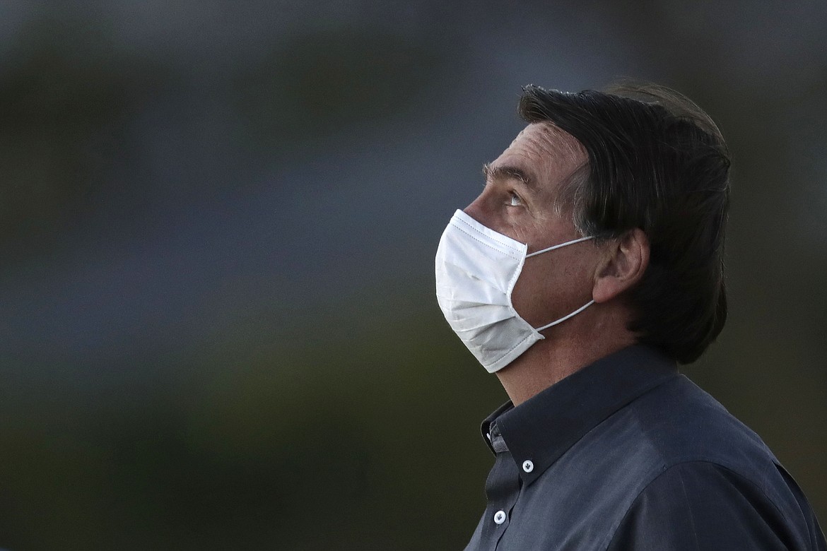 Brazil's President Jair Bolsonaro, who tested positive for  COVID-19, wearing a protective face mask attends a Brazilian flag retreat ceremony outside the Alvorada Palace, in Brasilia, Brazil, Monday, July 20, 2020. (AP Photo/Eraldo Peres)