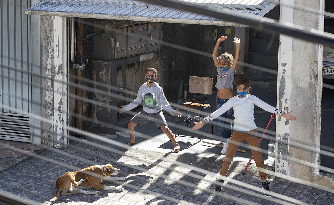 Children exercise from the rooftop of their building during and outdoor workout class imparted by physical trainer Ivan Nascimento for his neighbors during a quarantine imposed by the state government to help contain the spread of the new coronavirus in the Brasilandia neighborhood of Sao Paulo, Brazil, Sunday, May 17, 2020. (AP Photo/Andre Penner)