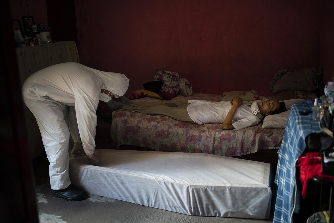 A worker of SOS Funeral, wearing protection equipment, prepares to remove the body of Eldon Cascais, who according to relatives, had pre-existing conditions and died at his house after having trouble breathing, amid the new coronavirus outbreak in Manaus, Brazil, Saturday, May 9, 2020. (AP Photo/Felipe Dana)