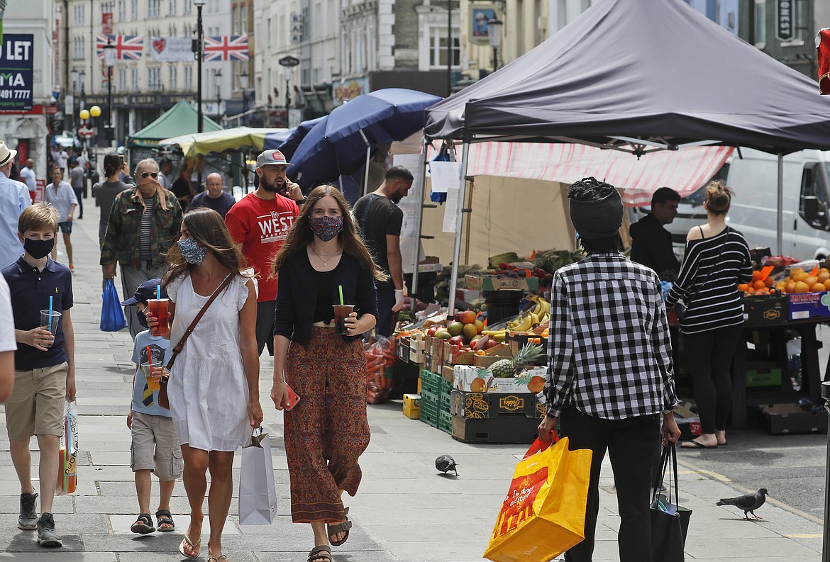 Customers walk along Portobello Road Market in London, Wednesday, May 27, 2020.  Following the gradual easing of the COVID-19 lockdown, street markets will be allowed to reopen in Britain from Monday onwards. (AP Photo/Frank Augstein)