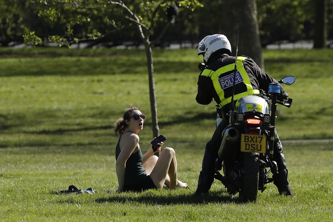 A woman is told to go home by a police officer on a motorbike to stop the spread of coronavirus and keep the park open for people observing the British government's guidance of social distancing, only using parks for dog walking, one form of exercise a day, like a run, walk, or cycle alone or with members of the same household, on Primrose Hill in London, Sunday, April 5, 2020. The new coronavirus causes mild or moderate symptoms for most people, but for some, especially older adults and people with existing health problems, it can cause more severe illness or death. (AP Photo/Matt Dunham)