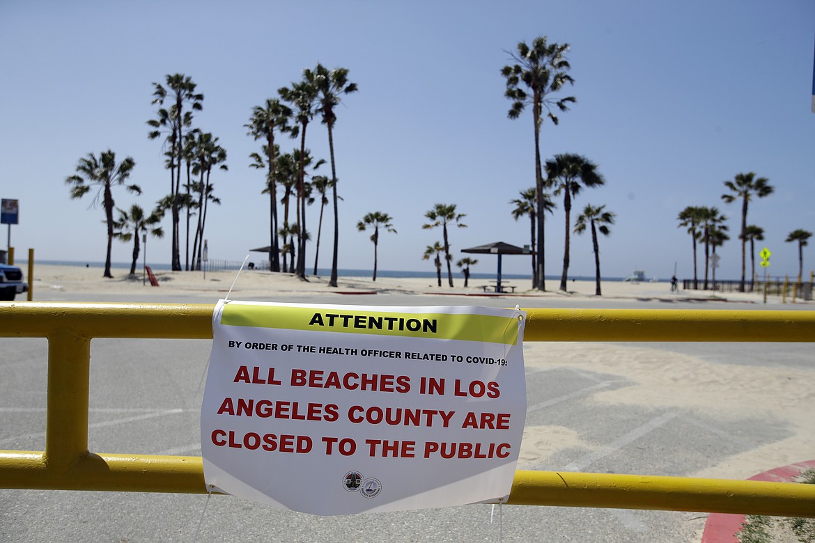 A closure sign is placed at the entrance of a beach front parking lot Sunday, March 29, 2020, in the Venice beach section of Los Angeles. With cases of coronavirus surging and the death toll increasing, lawmakers are pleading with cooped-up Californians to spend a second weekend at home to slow the spread of the infections. (AP Photo/Marcio Jose Sanchez)