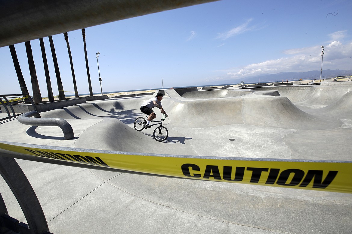 A lone biker uses the closed-off Venice Beach skatepark Sunday, March 29, 2020, in Los Angeles. With cases of coronavirus surging and the death toll increasing, lawmakers are pleading with cooped-up Californians to spend a second weekend at home to slow the spread of the infections. (AP Photo/Marcio Jose Sanchez)